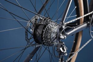 Roue vélo, cassette, chaîne, dérailleur, fond bleu.