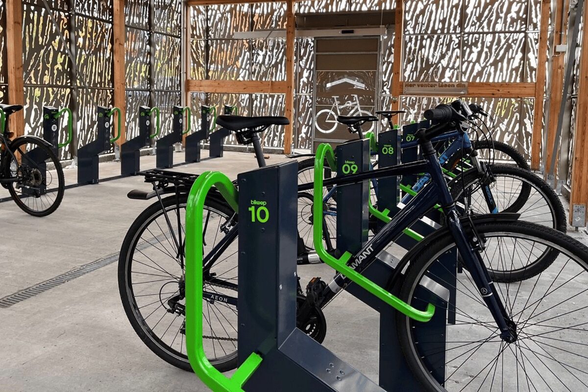 Vélos noirs garés dans une station de parking sécurisée et intelligente Bikeep avec des arceaux de verrouillage verts.