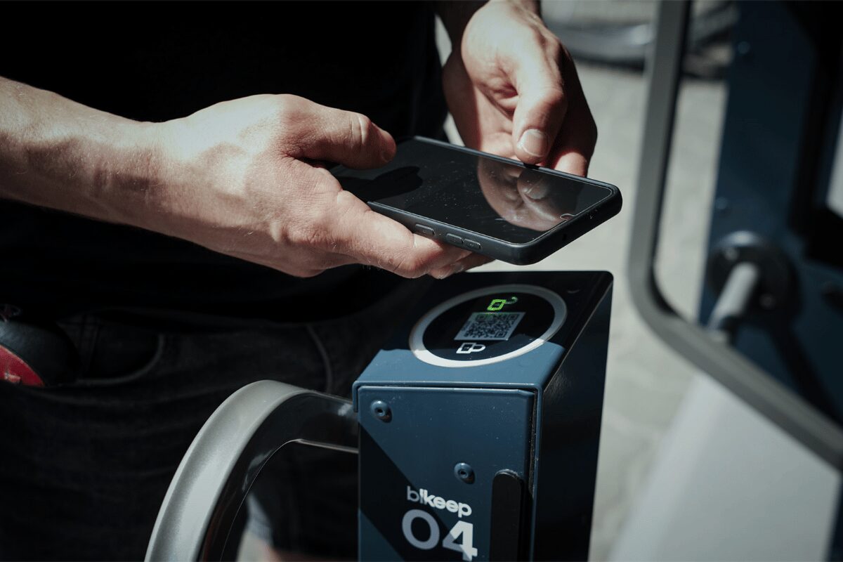 Utilisateur scannant un QR code avec son smartphone sur une borne de stationnement pour vélos Bikeep.