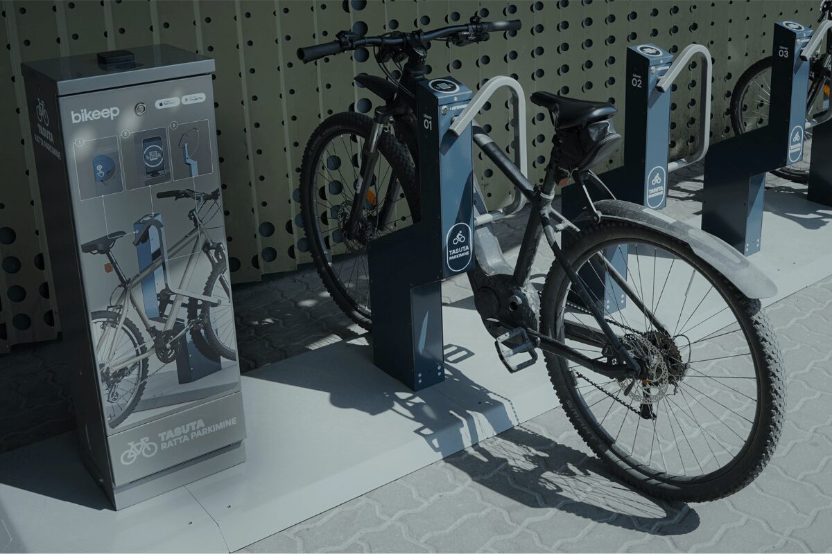Station de parking gratuit Bikeep avec un vélo électrique sécurisé, à côté d'un panneau d'information.